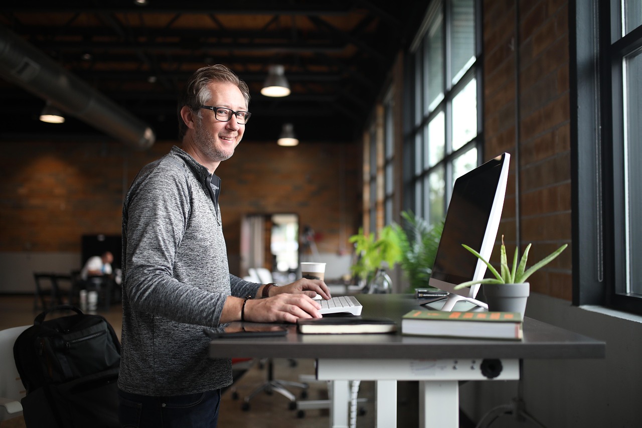 Thuiswerkplek met verstelbaar staand bureau en plant.